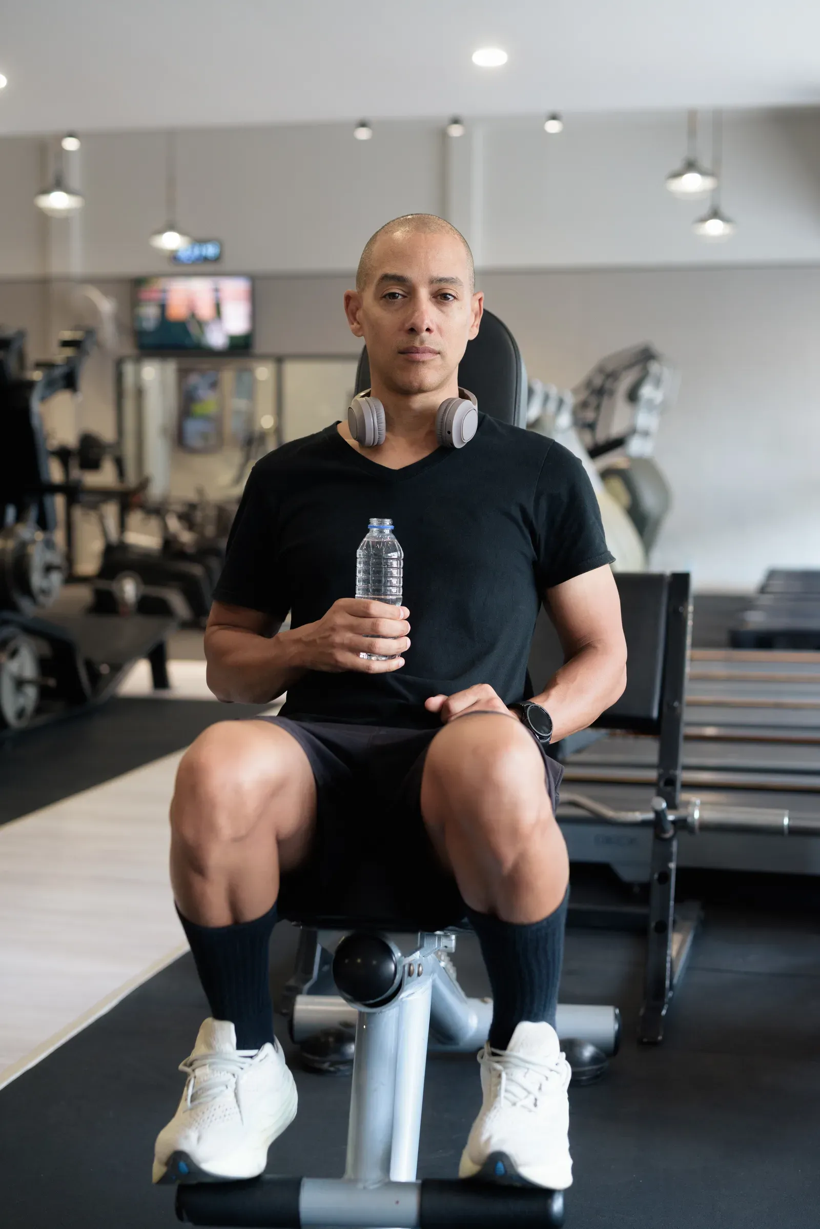 Bald man sitting on a gym bench with a water bottle