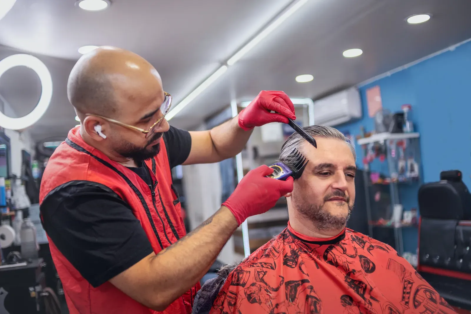 Barber in red gloves giving a client a fade haircut