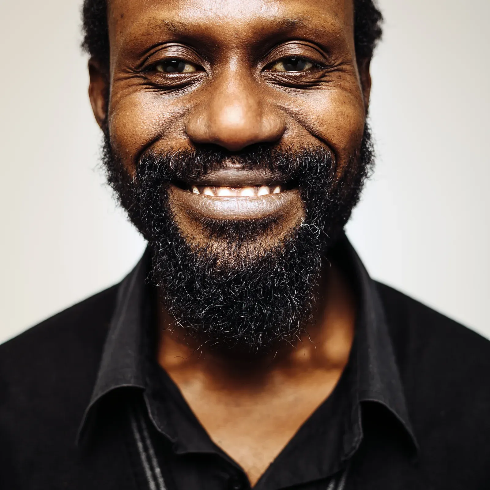 Smiling man with short hair and a full black beard