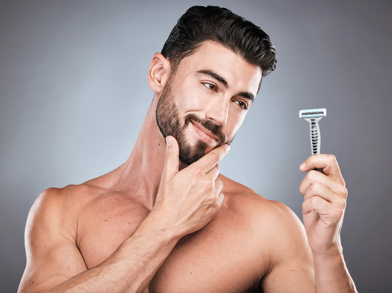 Smiling man with stubble holding a disposable razor