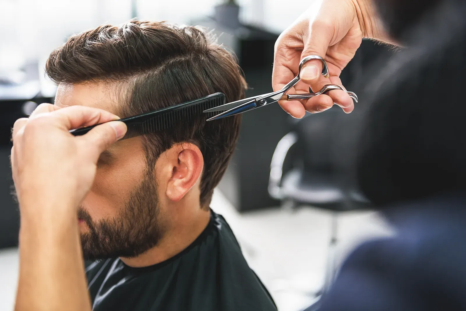 Barber cutting a client’s hair with scissors and comb