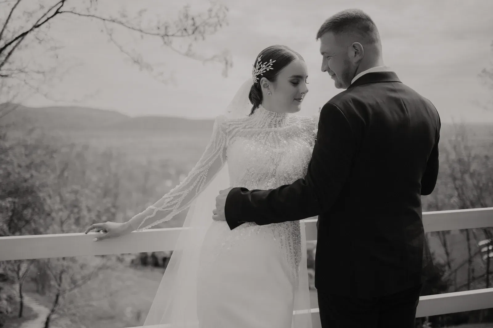 Black and white photo of a groom in a suit with his bride